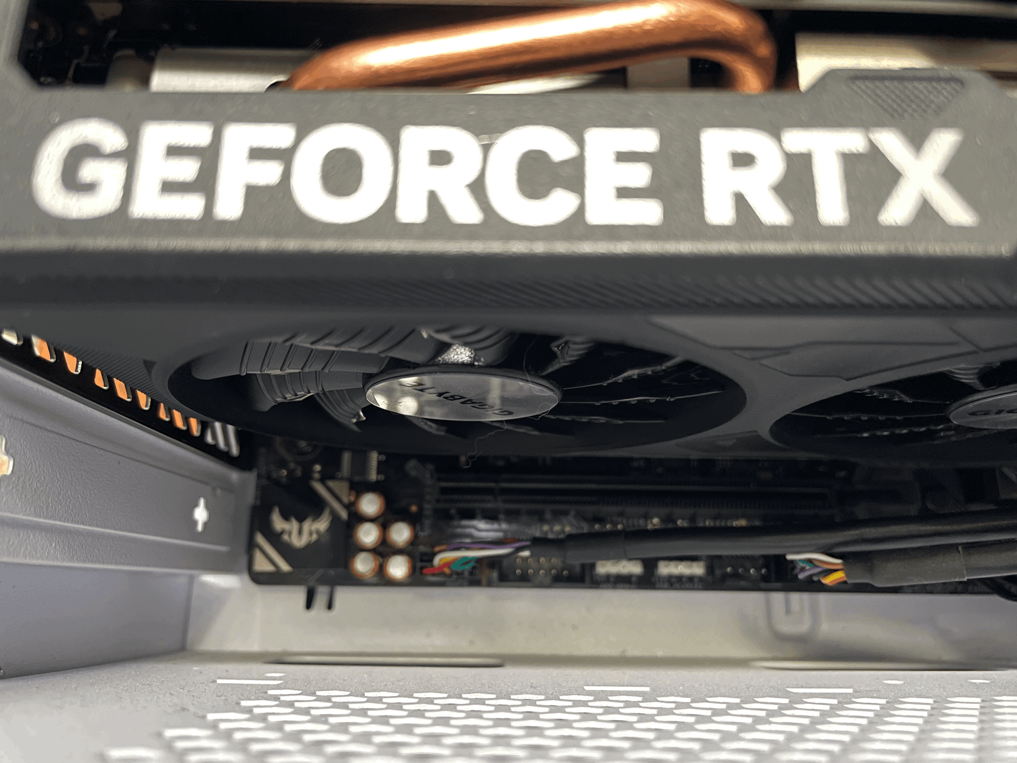 A close up picture of a graphics card slotted into the motherboard, seen from below, the words GEFORCE RTX on the side