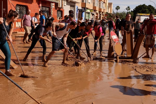 A large group of people sweep mud off the streets in Valencia, Spain after major flooding.